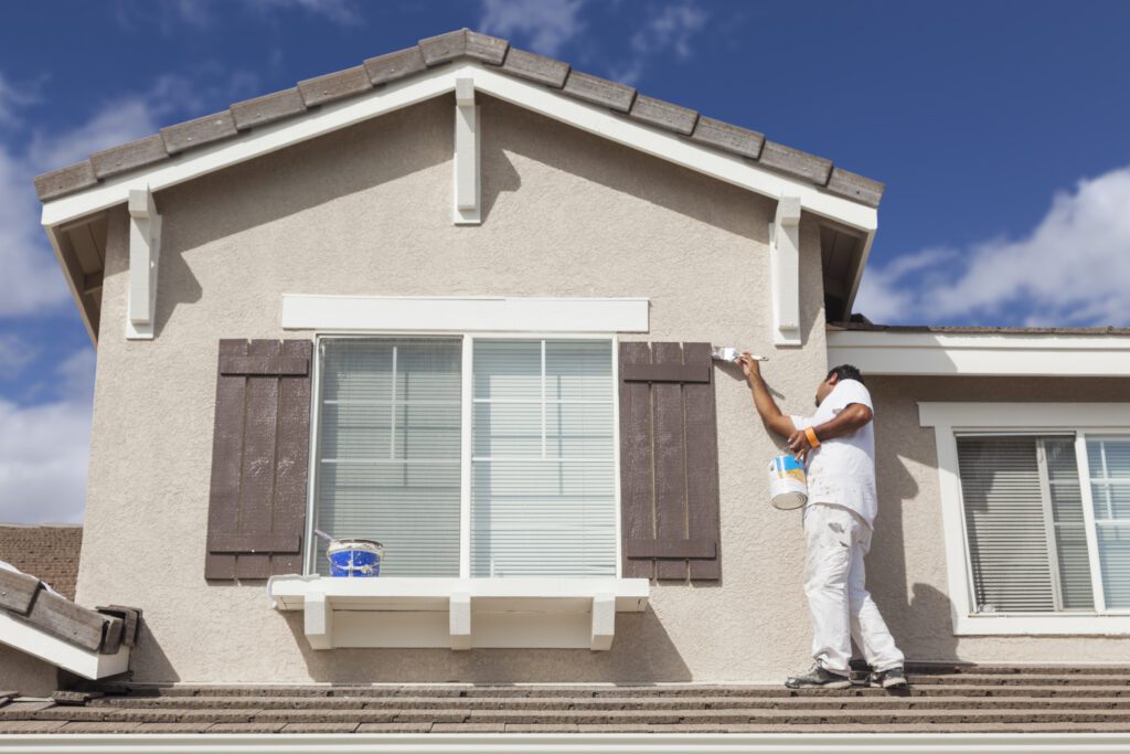 Busy House Painter Painting the Trim And Shutters of A Home.