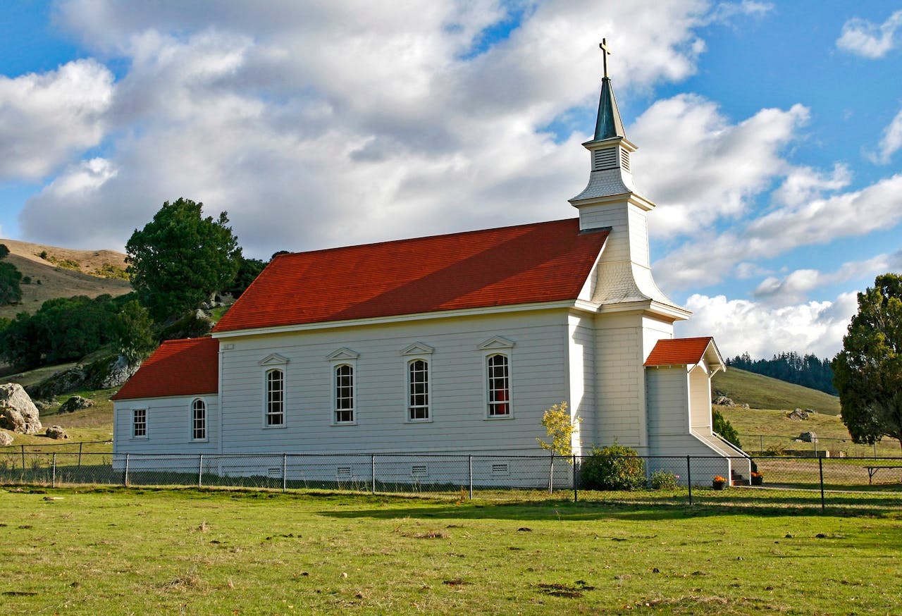 Red and White Concrete Church on Green Grass Field